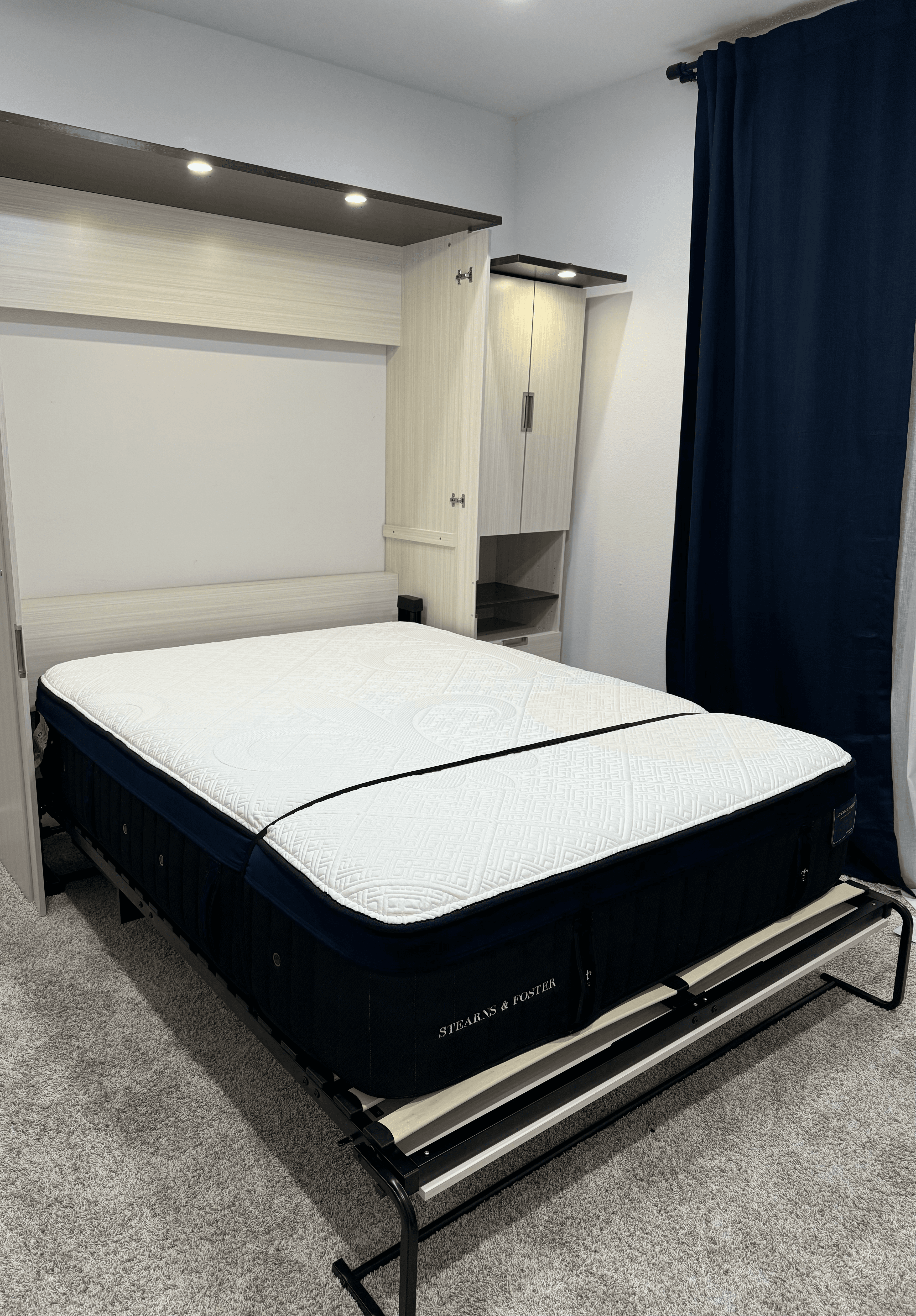 Stearns & Foster mattress on a metal Murphy bed frame pulled down from wall cabinetry.